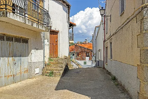 Calle estrecha con casas blancas y un cielo con nubes en Molinillo.