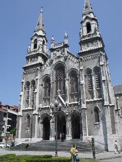 Gothic church facade with tall towers and large windows in Avilés.
