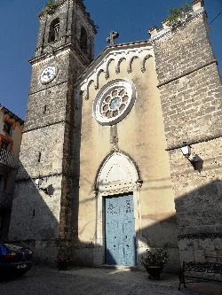 Facade of the church with clock and blue door in Alfafara.