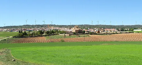 Landschaft mit grünen Feldern, Windmühlen und Stadt im Hintergrund.