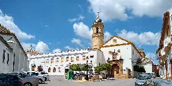 Square with church, tower, and cars in Morón de la Frontera