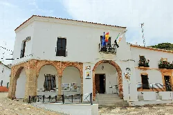White building with brick arches and flags on the balcony.