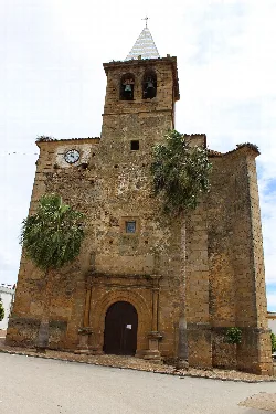 Facade of an old church with two palm trees at the entrance.