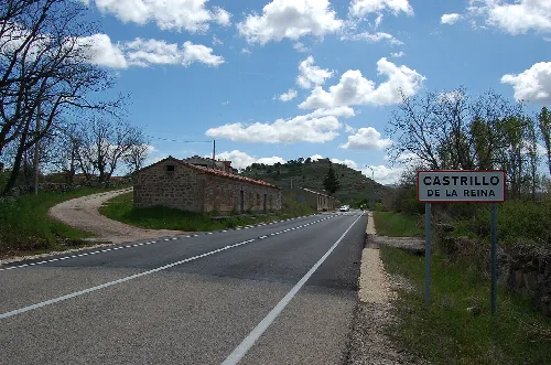 Entrance to Castrillo de la Reina on the CL-117 road with sign and rural landscape.
