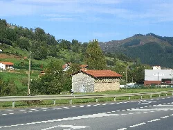 Small stone hermitage with red tiled roof next to the road.