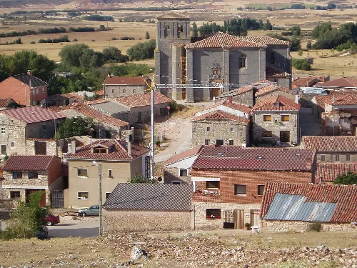 Houses and a church in a village with fields in the background.