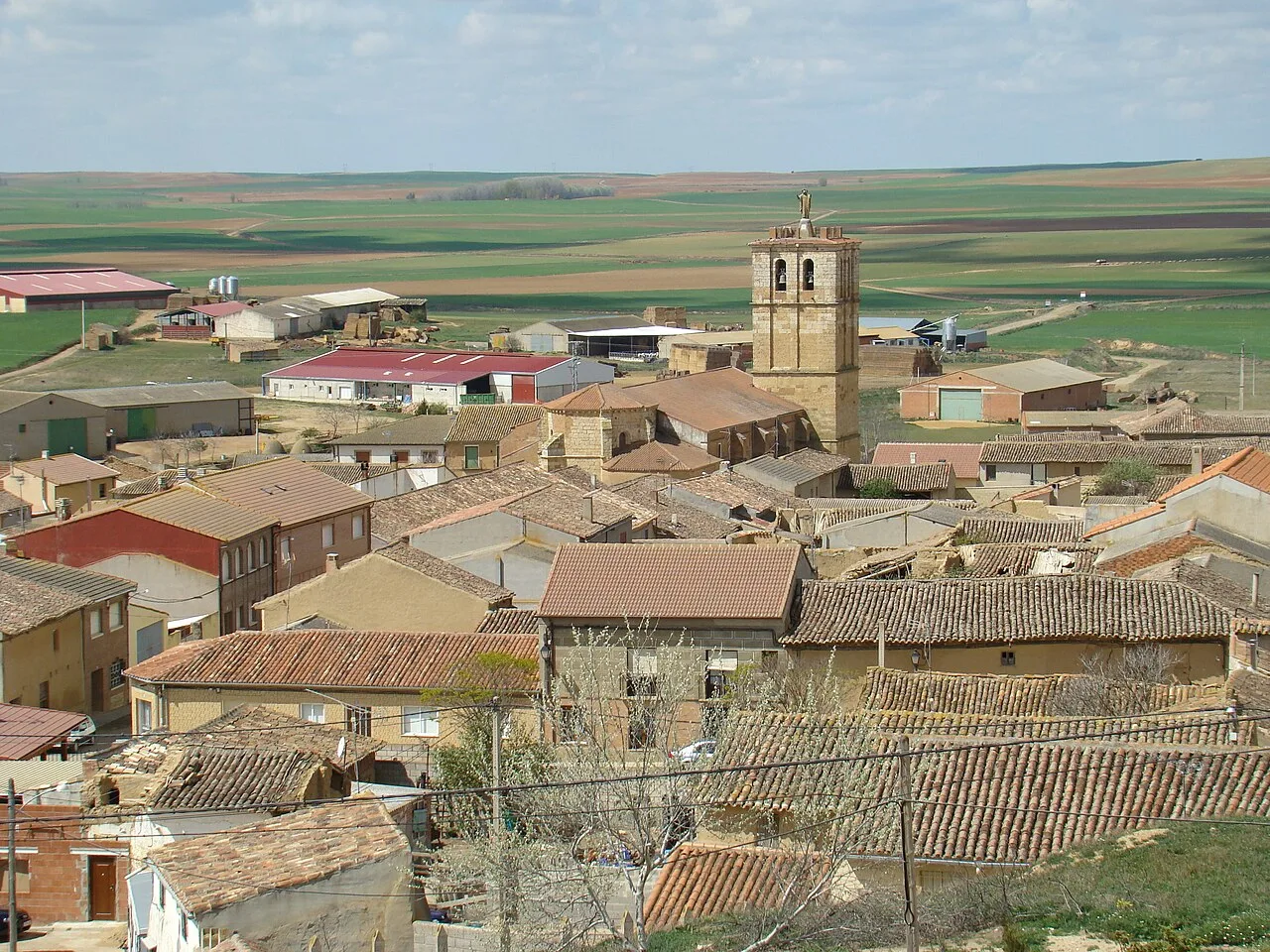 Luftaufnahme eines Dorfes mit Häusern und einer Kirche in Aguilar de Campos.