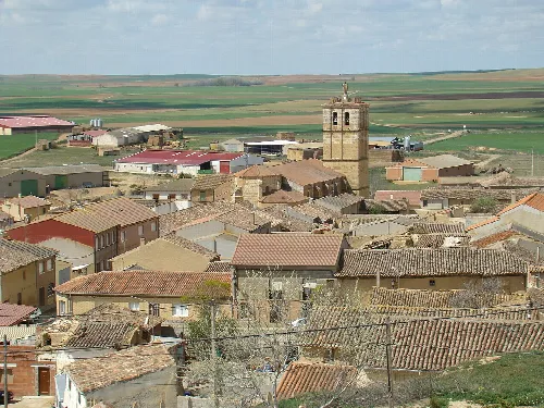 Vista aérea de un pueblo con casas y una iglesia en Aguilar de Campos.
