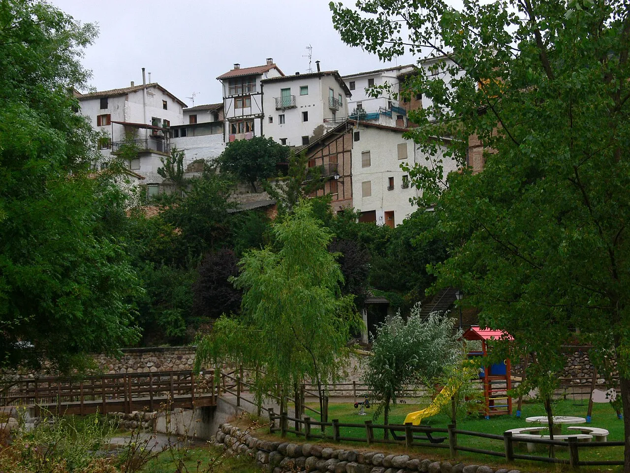 White houses on hillside and park with trees and playground in Pedroso.