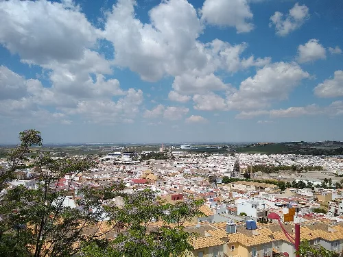 Blick auf Morón de la Frontera mit Häusern und Gebäuden unter einem bewölkten Himmel.