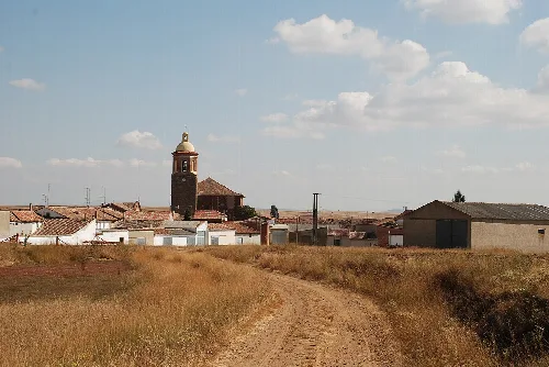 Dirt road with church and bell tower in Villasarracino, Palencia.