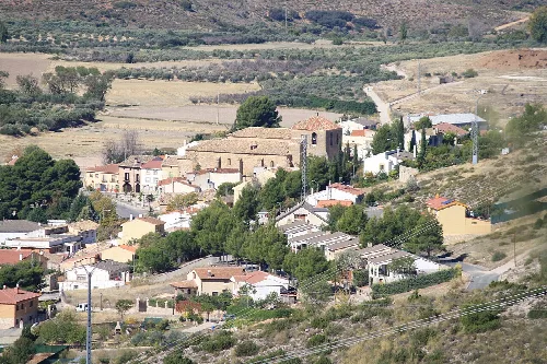 Panoramablick auf eine Stadt in einer bergigen Landschaft mit Häusern und Bäumen.