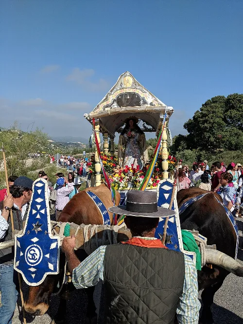 Dekorierter Wagen bei der Romería in Pruna mit vielen Menschen drumherum.