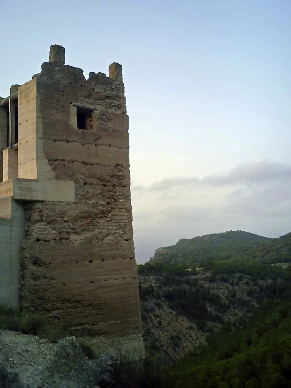 Stone castle tower in Pliego with green hills behind.
