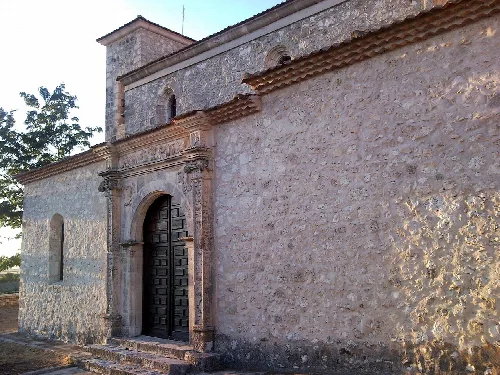 Church facade with wooden door and stone walls in Calabazas de Fuentidueña.