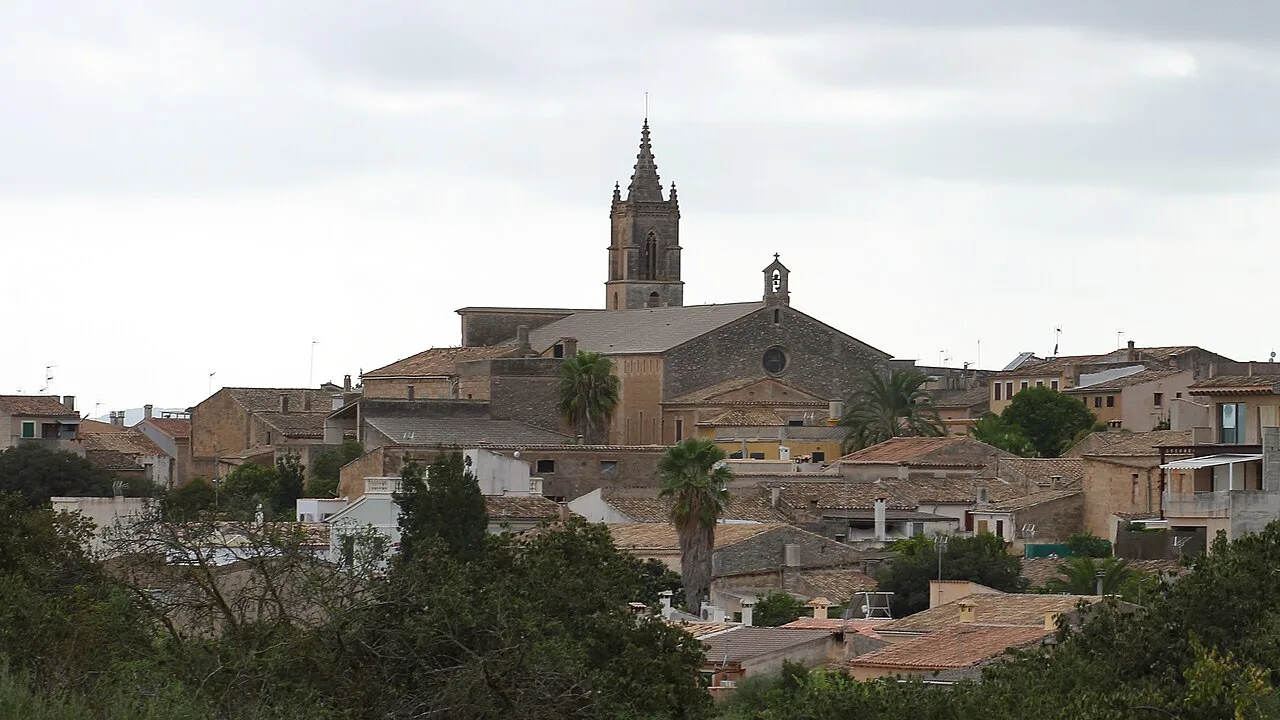 Vista de un pueblo con iglesia y casas de tejado de tejas en un día nublado.
