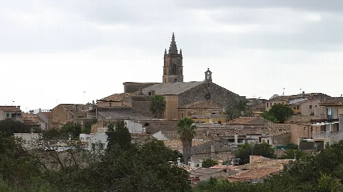 Vista de un pueblo con iglesia y casas de tejado de tejas en un día nublado.