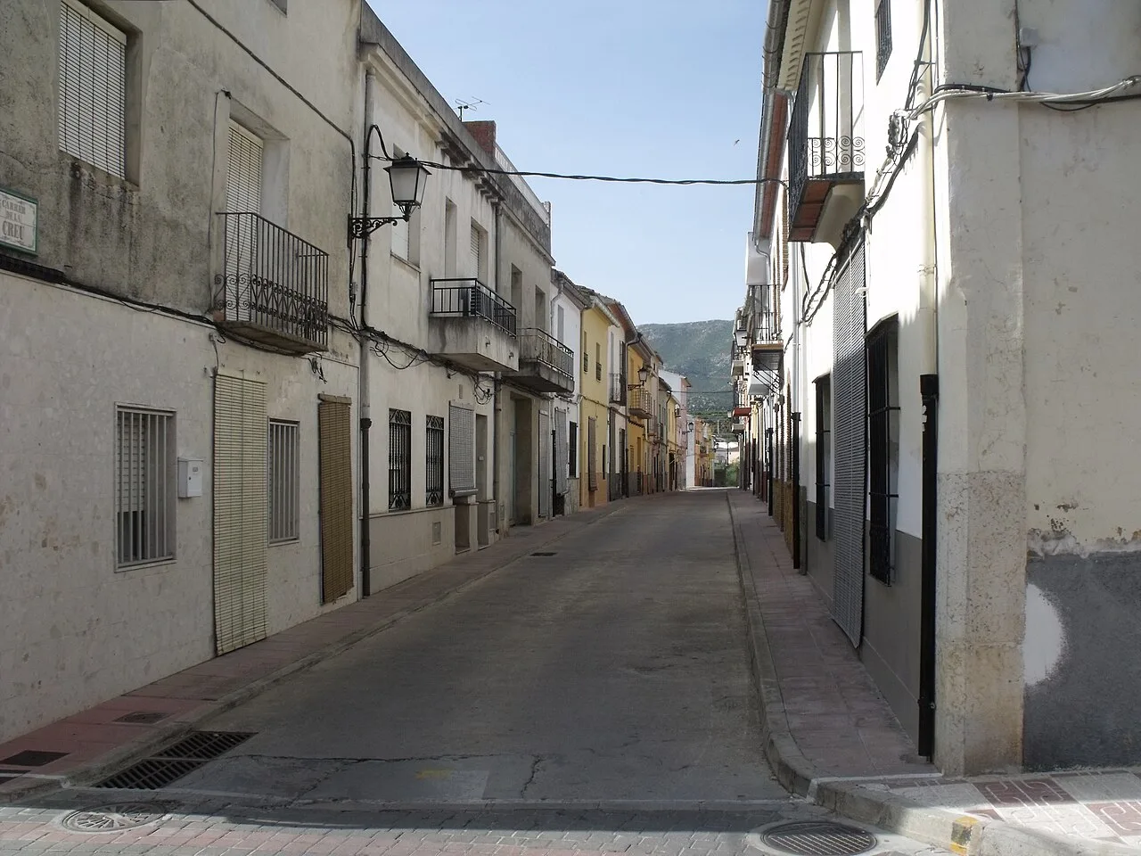 Blick auf eine ruhige Straße mit Häusern und Laternen in Almiserat
