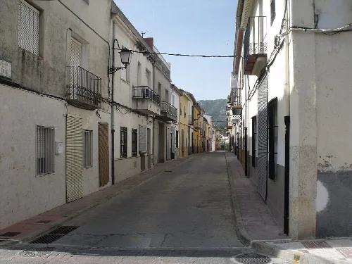 Blick auf eine ruhige Straße mit Häusern und Laternen in Almiserat
