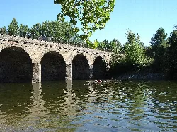 Stone bridge with arches over the river in Pinofranqueado.