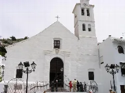 White facade of San Antonio Church in Frigiliana with tower and large door.