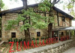 Museum entrance with trees and a sign on the sidewalk.
