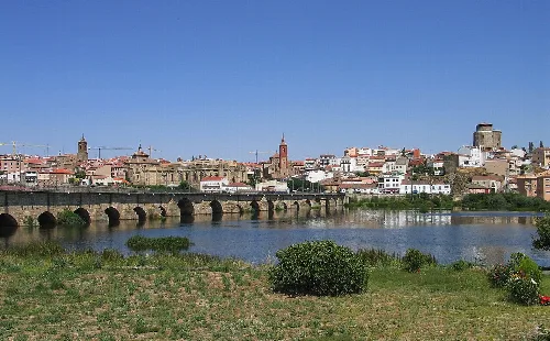 View of the Tormes River and the old town of Alba de Tormes with bridge and historic buildings.