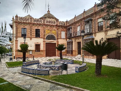 Fassade der Eremitage San Juan de Letrán mit Brunnen und Palmen in einem Park.