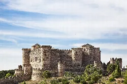 Mittelalterliches Schloss mit Türmen und Mauern an einem sonnigen Tag.