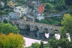 Roman bridge of Lugo over the river, surrounded by greenery and houses.