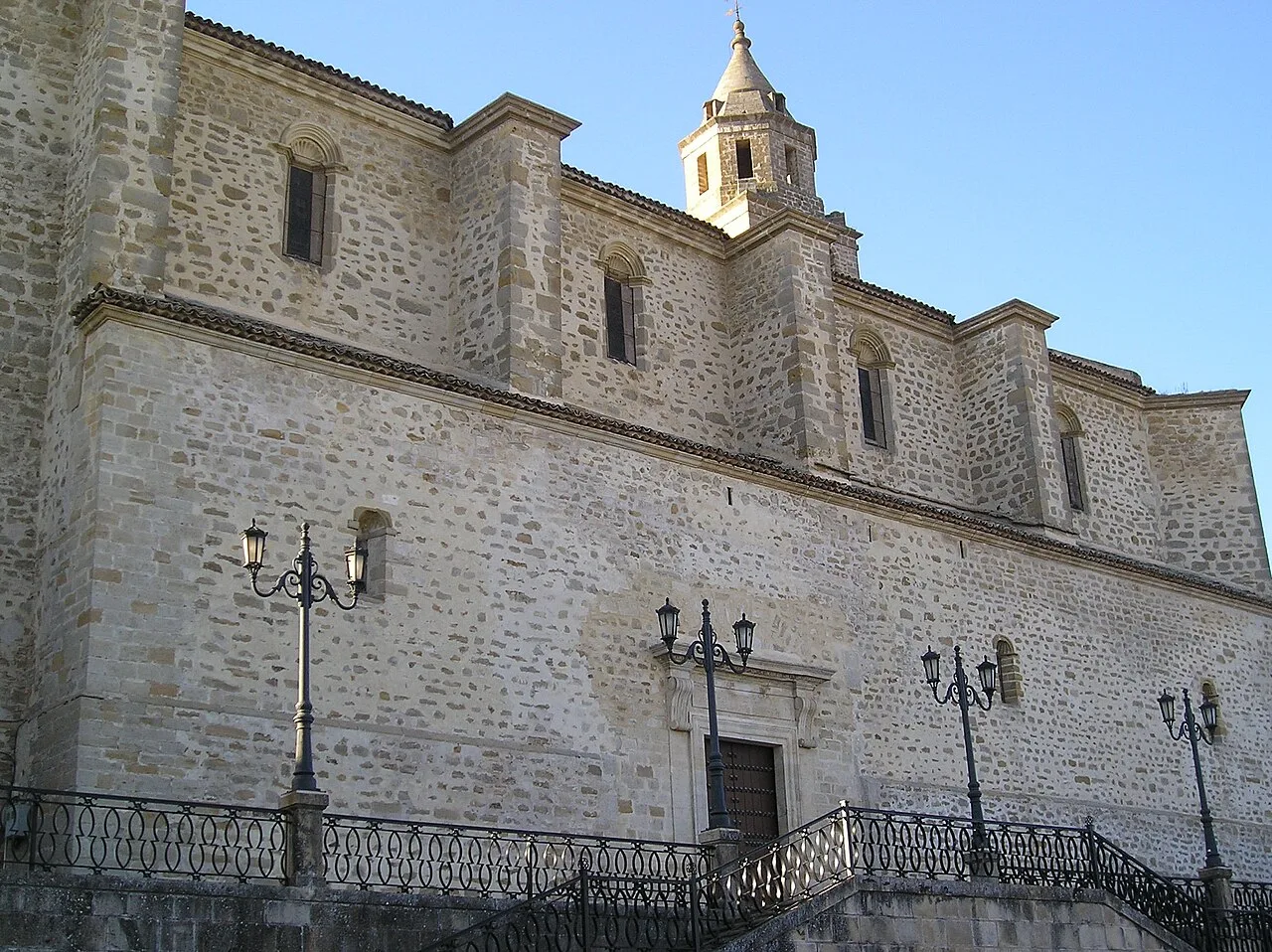 Seitenansicht einer Steinkirche mit Fenstern und Laternen an der Fassade.