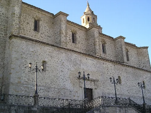 Seitenansicht einer Steinkirche mit Fenstern und Laternen an der Fassade.