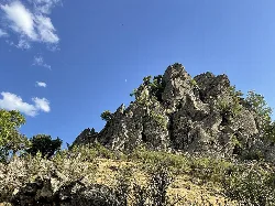 Formación rocosa con árboles y cielo azul en Noguera de Albarracín.