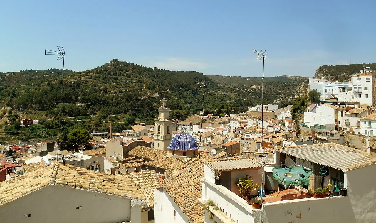 Panorámica del castillo y las casas de Buñol con colinas verdes al fondo.