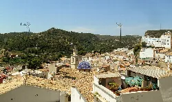 Panorámica del castillo y las casas de Buñol con colinas verdes al fondo.