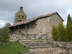 Kleine Steinkirche mit Glockenturm und Treppen in einer natürlichen Umgebung.