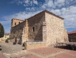 Iglesia de San Andrés, Berlangas de Roa, con paredes de piedra y un cielo azul con nubes.