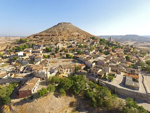 Vista aérea de un pueblo con casas y una colina en el fondo.