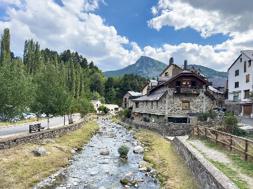 Stein- und Holzhäuser neben einem Bach in Sallent de Gállego.