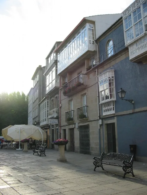 Straße mit alten Gebäuden und blumengeschmückten Balkonen in Padrón.