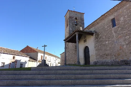 Church of San Bartolomé with tower and cross in the square.