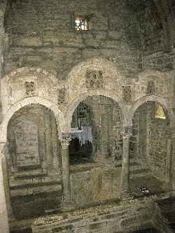 Interior of an old church with stone arches and decorated columns.