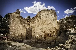 Ruins of an old hermitage with crumbling walls and a cloudy sky.