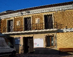 Building with a decorated facade in gold tones and a balcony in the town hall square.