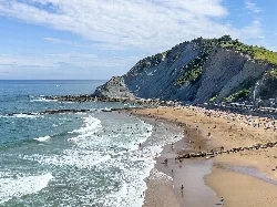 View of Itzurun beach with cliffs and people on the sand.
