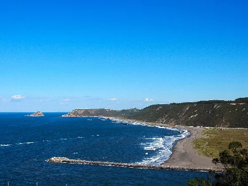 Vista de la playa de los Quebrantos con acantilados y mar en un día soleado.
