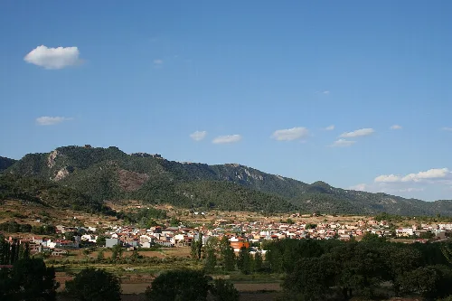 Paisaje con montañas y pueblo en un día soleado.