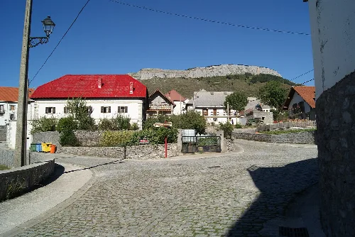 Straßen und Häuser in Villanueva de Aézcoa mit einem Berg im Hintergrund.