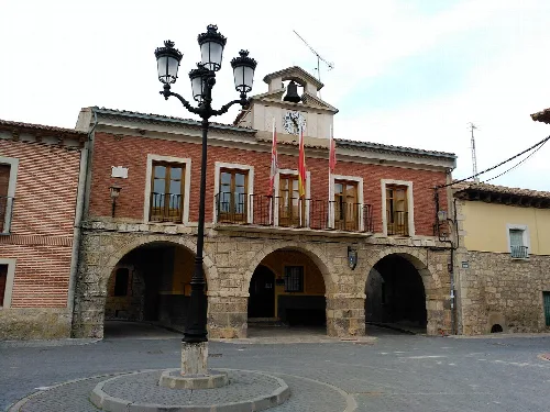 Casa consistorial de Valdenebro de los Valles con arcos y reloj en la torre.