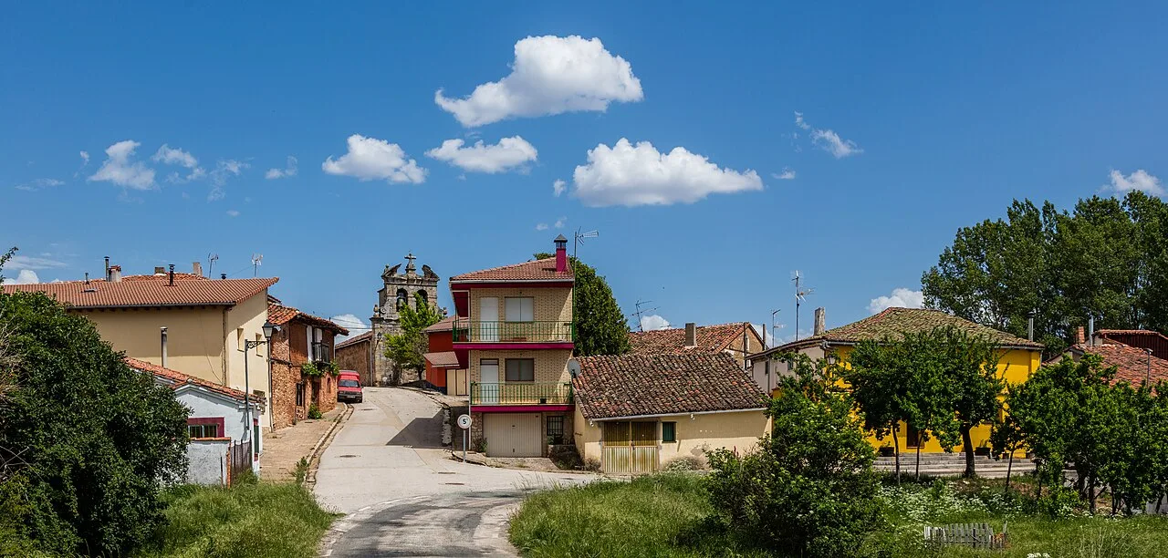 Houses and road in Cubilla, Soria, with trees and blue sky with clouds.